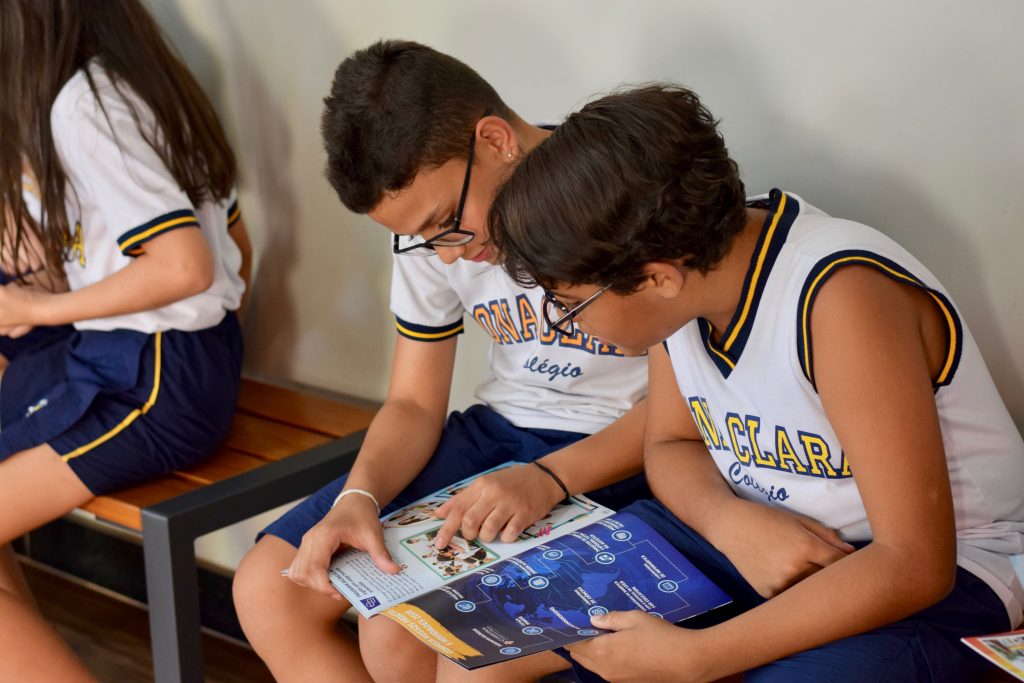 Duas crianças lendo um material podem apresentar dificuldades de concentração como impacto das aulas remotas